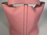 a pink leather bag with a metal handle and a metal handle