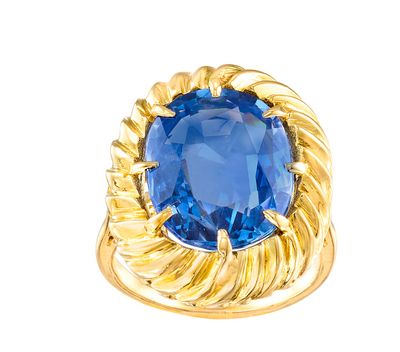 gros plan d'une bague en or avec une pierre bleue
