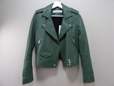 green leather jacket hanging on a hanger on a wall