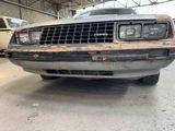 a rusted car parked in a garage with other cars in the background