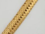 gros plan d'un bracelet en or sur une surface blanche