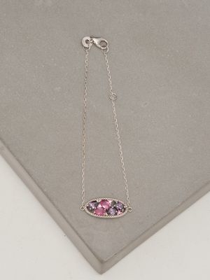 un gros plan d'un collier rose et violet posé sur une surface blanche
