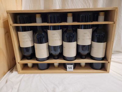 des bouteilles de vin rouge dans un coffret en bois posé sur un drap blanc