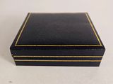a black box with gold trim sitting on top of a white table