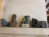 three statues on a shelf with a vase on it