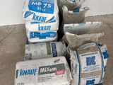 many bags of cement on a pallet next to a wall