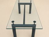 une table en verre avec deux pieds noirs et un plateau en verre
