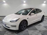 the white tesla model 3 is parked in a room with a checkered floor