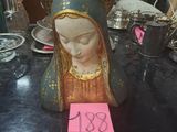 une statue de la Vierge Marie posée sur une table, avec un mot posé dessus