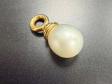 un pendentif plaqué or orné d'une perle blanche sur un fond noir