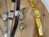 three watches and a watch band on a wooden board