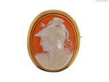 une broche camée représentant le profil d'une femme, de couleur orange et blanche