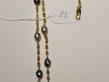 a close up of a gold chain with black pearls on it
