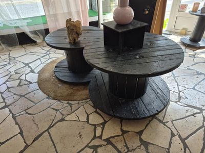 deux tables fabriquées à partir de bobines en bois, posées à même le sol