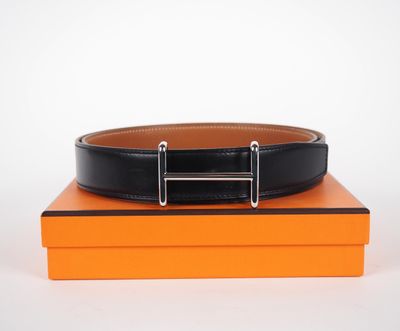 un gros plan d'une ceinture noire posée sur une boîte orange