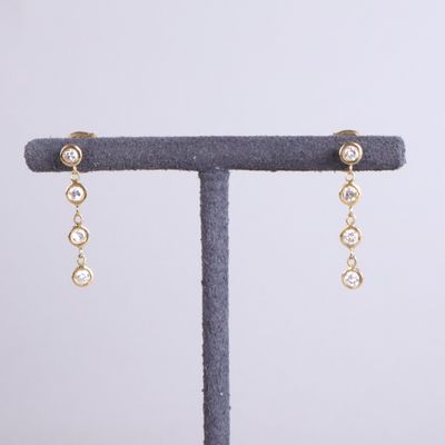 une paire de boucles d'oreilles en or et diamants, présentée sur un présentoir