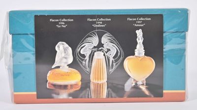 une boîte contenant trois flacons de parfum, posée sur une table