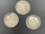 three silver coins sitting on top of a black surface