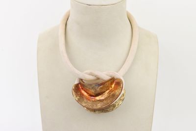 un mannequin blanc portant un collier doré et rouge