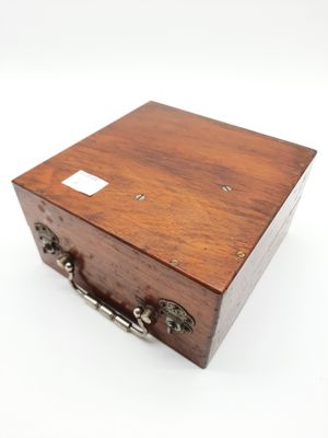 une petite boîte en bois avec des poignées en métal, posée sur une surface blanche