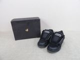 une paire de chaussures noires pour enfants devant une boîte noire