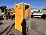 a man standing in front of a portable toilet in a parking lot