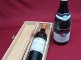 a bottle of wine in a wooden box next to a bottle of wine