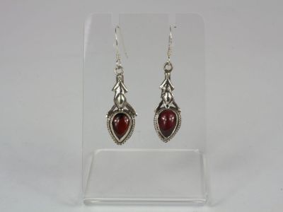 a pair of silver earrings with red stones on them