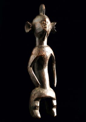 un gros plan d'une statue posée sur une surface noire, avec un fond noir