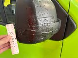 a hand that is holding a piece of paper next to a car mirror