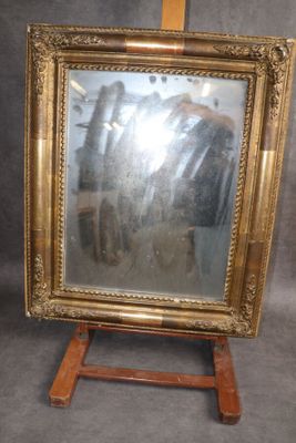 une photo d'un miroir à cadre doré posé sur un socle en bois