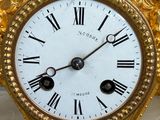 a gold clock with roman numerals on the face