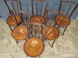 six wooden chairs are lined up in a row on a wooden floor