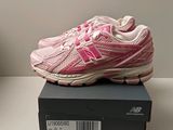 des chaussures de course roses et blanches posées sur une boîte noire posée sur une table