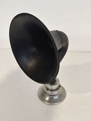 une image représentant une enceinte noire et argentée posée sur une surface blanche