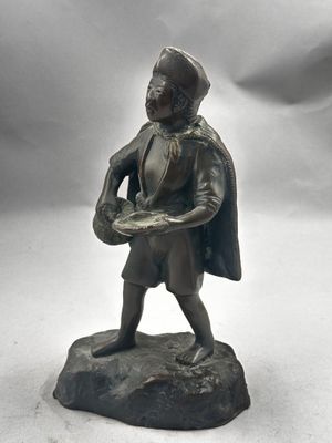 figurine en bronze représentant un homme tenant un plateau de nourriture posé sur un rocher