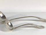 two silver spoons are sitting on top of a white surface