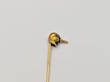 a gold stick with a bird on it on a white surface