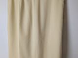 a beige skirt hanging on a hanger against a white wall
