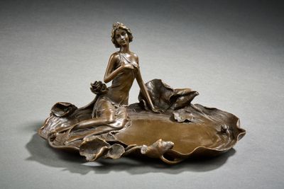 figurine en bronze représentant une femme assise sur une feuille, accompagnée d'un chien
