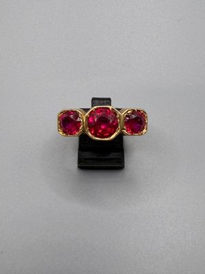 un gros plan d'une bague en pierre rouge posée sur un socle noir