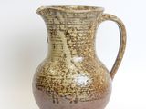 a brown vase with a handle sitting on a white surface