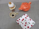 a teapot, a cupcake, a spoon, and a teapot on a table