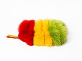 un gros plan sur un pompon rouge, jaune et vert posé sur une surface blanche