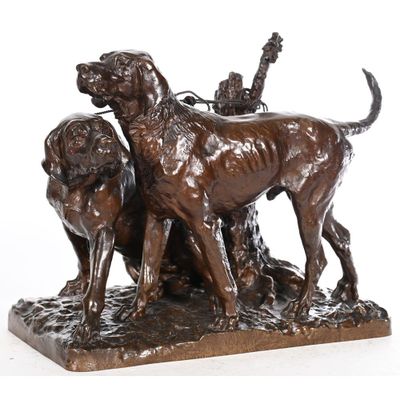 statue en bronze représentant deux chiens et un oiseau posés sur un rocher