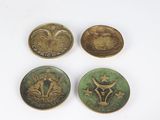 four antique brass buttons on a white surface