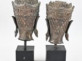 pair of bronze head vases on stands on a white background