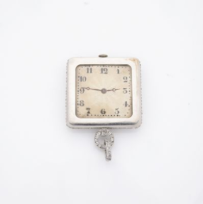une petite horloge à laquelle est accrochée une clé sur le côté
