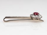 an image of a red stone and diamond broocher on a white surface