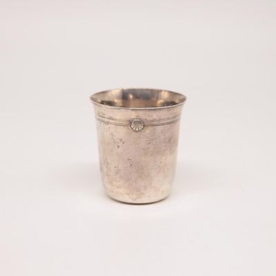 une tasse en argent posée sur une surface blanche